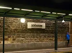 Het stationsbord op de ongepleisterde wand.