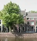 Hoekpand Brandersteeg met bakstenen lijstgevel ter breedte van vier vensterassen. Lage bovenverdieping. Geprofileerde vensterdorpels