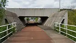 Onderdoorgang in talud Schipholdraaibrug; uiterst rechts een slagboom van de draaibrug; juni 2019.
