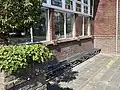 De oude schoolbankjes op het schoolplein. Hierop konden de kinderen buiten wachten als zij te vroeg op school arriveerde.