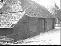 Houten schuur met stro en pannen gedekt, gedeeltelijk met aankubbingen