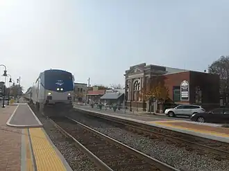 2009: Trein van Northeast Regional stopt op straat; het dubbelspoor ligt in het midden, aan beide zijden ligt de straat. Ook is een historisch voormalig station te zien.