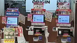 Een winkelinterieur met drie zelfbedieningskassa’s van Kitchen Origin in Osaka. De terminals staan in een rij opgesteld tegen een wand. Twee van de kassa’s zijn hoog geplaatst, geschikt voor staande klanten van gemiddelde lengte. De derde terminal is duidelijk lager gepositioneerd en ontworpen voor zittende gebruikers, zoals rolstoelgebruikers of personen van kleine lengte, bijvoorbeeld mensen met een skeletdysplasie.