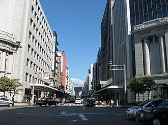 Zicht op Shijō-dōri vanaf het kruispunt Shijō-Karasuma. Er bevindt zich een ingang naar het station onder het gebouw van de Mitsubishi Bank.
