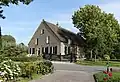 Goed bewaarde, eenvoudige boerderij, met hoog, rieten dak, dat woon- en bedrijfsgedeelte overdekt. De van vlechtingen voorziene puntgevel van het woonhuis heeft een bovenlicht met gietijzeren levensboom en vensters met luiken en zesruitsramen. De stal heeft getoogde venstertjes