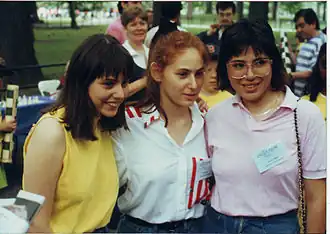 De drie jonge Polgár zussen - links staat Sofia, in het midden Judit en rechts Susan - poseren samen buiten voor een foto in 1988. Ze staan dicht bij elkaar. De achtergrond toont een natuurlijke omgeving, vermoedelijk is er een schaakevenement gaande.