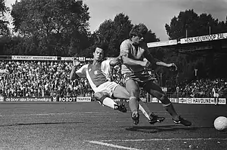 Henk van der Vlag (rechts) namens FC Utrecht in duel met Amsterdammer Ton Blanker (Ajax-FC Utrecht 3-2, 23-9-1979). FC Utrecht eindigde in het seizoen 1979-1980 als 5de van de 18 eredivisieclubs en mocht daardoor in het seizoen 1980-1981 Europa Cup III-voetbal spelen, Ajax werd landskampioen.