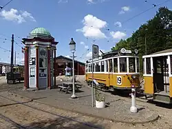 Telefoonkiosk en ander historisch straatmeubilair uit Frederiksberg in Kopenhagen. De tram erachter is de KS 327 (bouwjaar 1912).