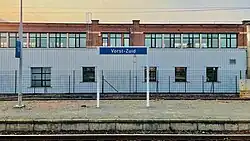 Een plaatsnaambord op een perron