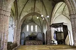 Interieur vanuit een van de zijbeuken met herenbank en preekstoel