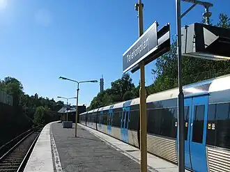 Het perron gezien vanuit de tunnelingang, rechts boven de bomen de toren van de telefoonfabriek
