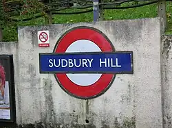 Een roundel op het betonnen hek langs het perron.