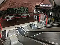 De roltrappen aan de zuidkant met wandschildering tussen de twee perrons.