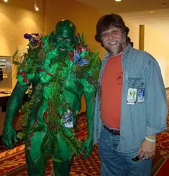 Een fan gekleed als Swamp Thing, samen met Len Wein