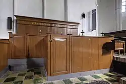 19e-eeuwse bank voor de kerkvoogden en notabelen met een offerkist ervoor