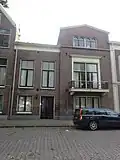Rechtervleugel van een symmetrisch opgezet blok herenhuizen. Rechts een hoekpaviljoen met driehoekige afdekking. Balkon op gesneden consoles en met ijzeren balkonhek
