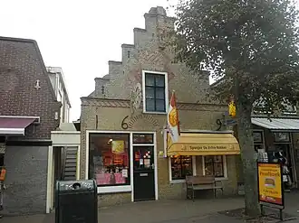 Pand met moderne winkelpui in versierde trapgevel van gele en rode steen en achtertopgevel