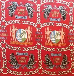 Angisa (hoofddoek) ter herdenking dat 100 jaar geleden de slavernij in Suriname werd afgeschaft. Op een rode ondergrond is tweemaal het wapen van Suriname afgebeeld met daartussen de jaartallen 1863 en 1963 en 1 juli.