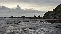 Bij de ruwe noordkust van de baai liggen er enkele klippen en rotsen in het water