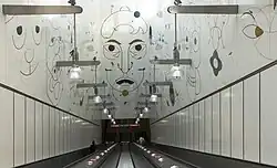 De roltrappen tussen de wandschildering.