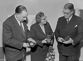 1959 uitreiking van de penningen van de Rotterdamse Kunststichting: dhr. G. van Dusseldorp en mej. mr. A.R. Werner bekijken de penning van de Maze; de penning van de Leuve was voor Wout van Heusden (links).