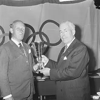 Van Karnebeek (rechts) reikt in 1965 de Van Tuyllbeker uit aan Ansco Dokkum, voorzitter van de Roeibond.