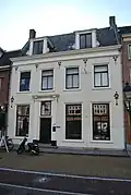 Huis met hoog zadeldak, waarop hoekschoorstenen