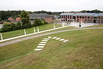 Uitzicht vanaf de zuidelijke heuvel, met de markering van de zuidelijke punt van het stenen schip en het wandelpad met de witte pilaren
