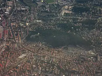 Luchtfoto met de beboste heuvel met daarop de kasteelruïne