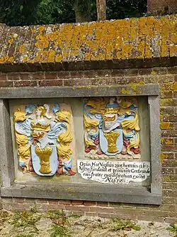 In de muur een gevelsteen uit 1572 van het in 1912 afgebroken Aytta-Godshuis