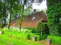 Kortgevelboerderij van één bouwlaag en een zadeldak met aan één zijde een schild en aan één zijde een wolfseind