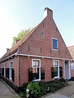 Visserswoning onder zadeldak tegen voortopgevel met moet van kleine rond gesloten lichtopening (Museum 't Fiskershúske)
