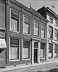Lijstgevel. Huis van parterre en verdieping. Deuromlijsting met verdiepte pilasters, gesneden deur en consoles onder de kroonlijst Lod. XIV