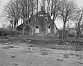 Grote boerderij met voorhuis onder zadeldak tussen afgeknotte topgevels (sinds 1977: gemeentehuis)