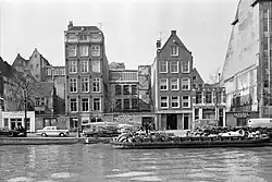 Bebouwing langs de Zwanenburgwal in verval; 1964. In de jaren tachtig is de gevelwand weer opgevuld met nieuwbouw. Rechts staat het gebouw dat vanaf de jaren 80 huisnummer 50-60 draagt