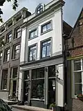 Huis met gepleisterde lijstgevel voorzien van hoekpilasters