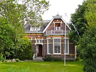 Vrijstaand woonhuis in overgangsstijl met toegangshek