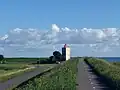 Dijk met fietspad, met in de bocht een rechthoekige witte vuurtoren