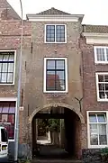 Door rechte lijst afgesloten woninggedeelte, gebouwd boven een doorgang met een natuurstenen poortboog aan de straat