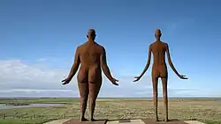 Een dikke en een dunne dame staan op de zeedijk te wachten op hoog water