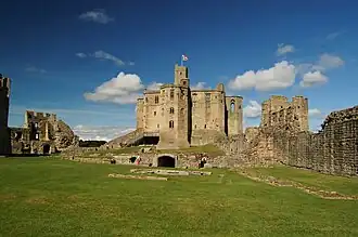 Nog redelijk intacte stenen toren omgeven door geruïneerde muren.