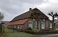 Langgevelboerderij van één bouwlaag en een afgewolfd zadeldak.