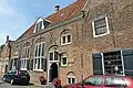 Huis met in- en uitgezwenkte, door horizontale lijsten en pilasters verlevendigde gevel