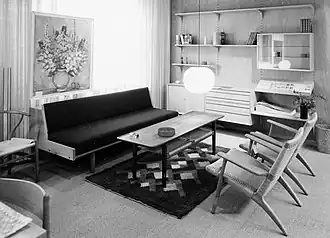 Zwart-wit foto van een toonzaal in meubelwinkel Linds Bolighus. Op de foto zijn onder meer een bank, salontafel, leunstoelen en een wandkast te zien.