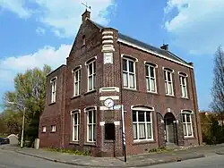 Het oude gemeentehuis van de gemeente Leens uit 1909. Het was oorspronkelijk witgepleisterd en had een torentje. Deze en andere elementen verdwenen bij een verbouwing in 1937.