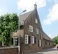 Een statige hoeve, T-huis, waarvan het rechts onderkelderde woonhuis een verdieping en een rieten zadeldak bezit