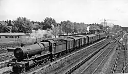 Een trein naar het westen passeert de melkoverslag, rechts op de achtergrond staat het stationsgebouw langs het viaduct