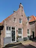 Huis met puntgevel, versierd met tussentrappen en toppilaster op consoles. Blijkens jaartalankers in 1789 verbouwd. Deur met ovale panelen en vensters met 12-ruits-schuiframen, begin 19e eeuw. Inwendig 17e-eeuwse sleutelstukken, 18e en 19e-eeuwse betimmeringen