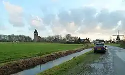 Silhouet van Westerwijtwerd vanaf de Dorpsweg met rechts de molen en links de kerk