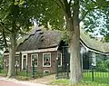 Stolphoeve. Dwarseind en een vrijwel vrijstaand woonhuis onder pannen zadeldak. Negenruits schuifvensters. Gevelsteen ter herinnering aan koninklijk bezoek in 1914